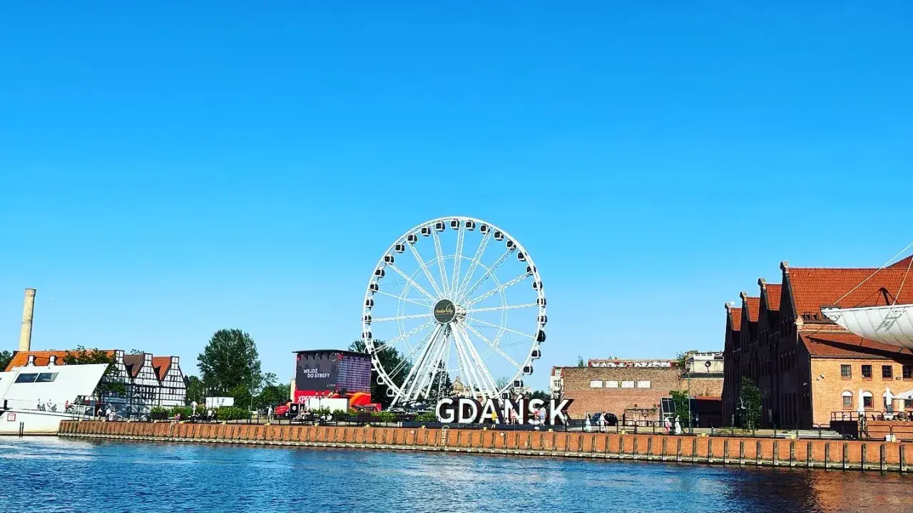 Stadsvy över Gdansk, Polen, med ett stort pariserhjul och byggnader längs floden.