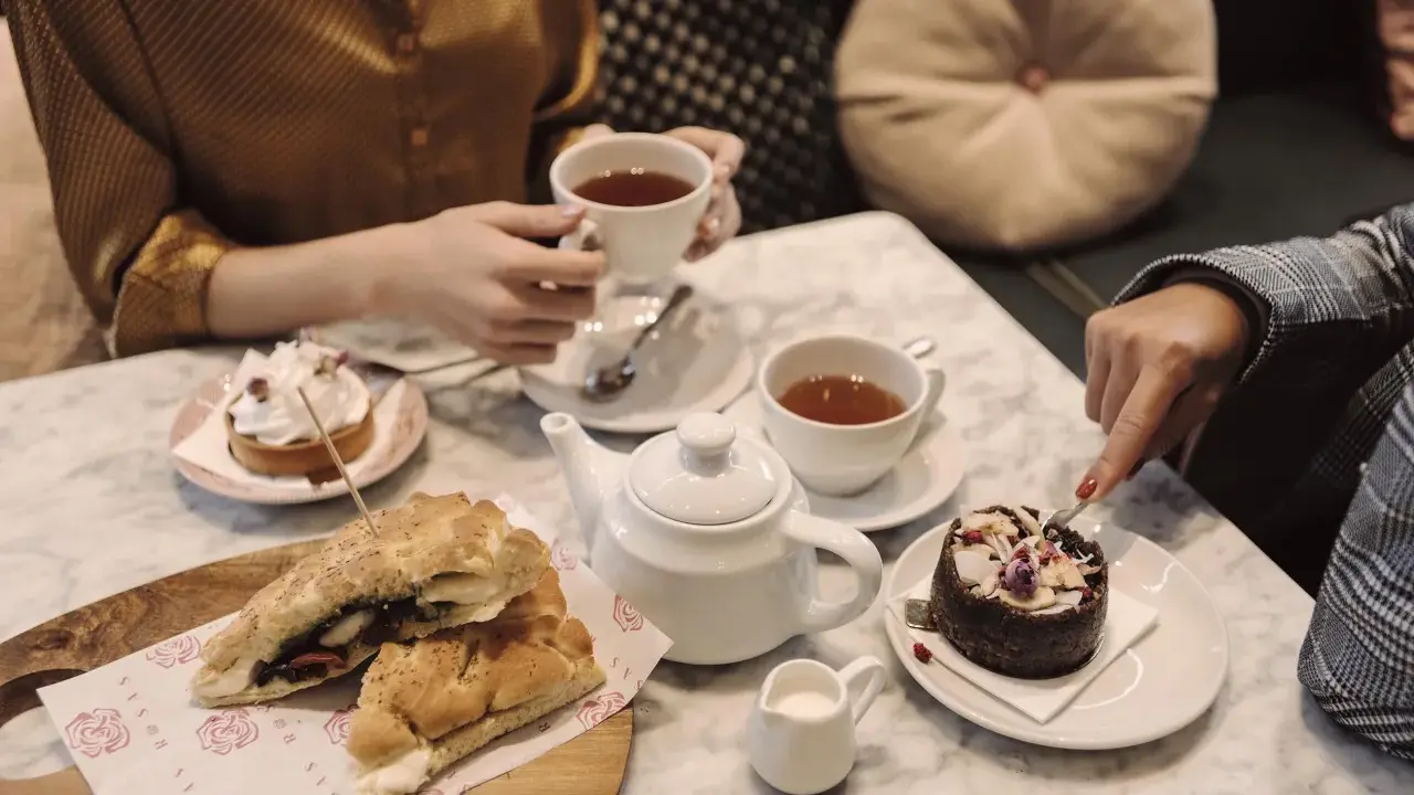 Två personer njuter av afternoon tea i Stockholm med smörgåsar och bakelser.