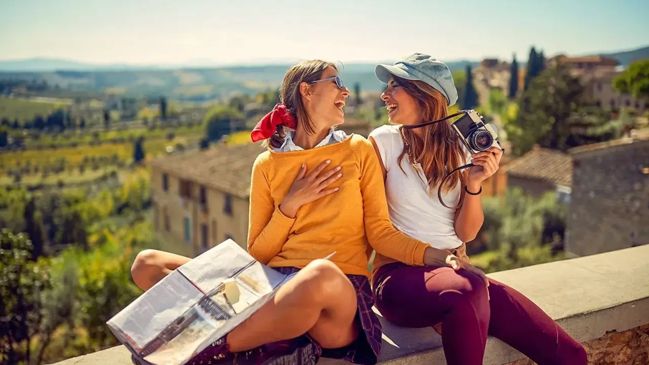 Två glada vänner njuter av sin resa i Europa, med en karta och kamera redo för nya äventyr i en vacker italiensk landskapsvy.