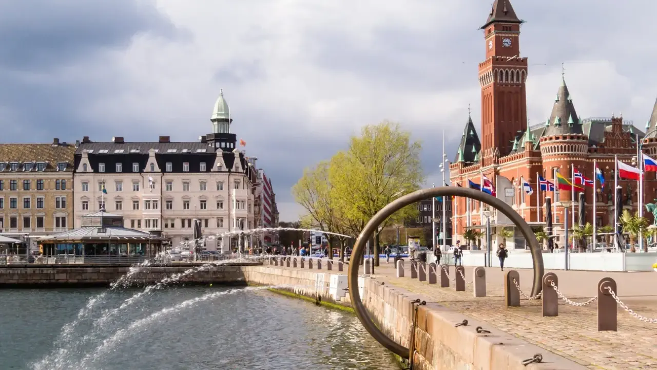 Vattenfontäner vid hamnen i Helsingborg, med Rådhuset i bakgrunden. Perfekt för en promenad bland sevärdheter.