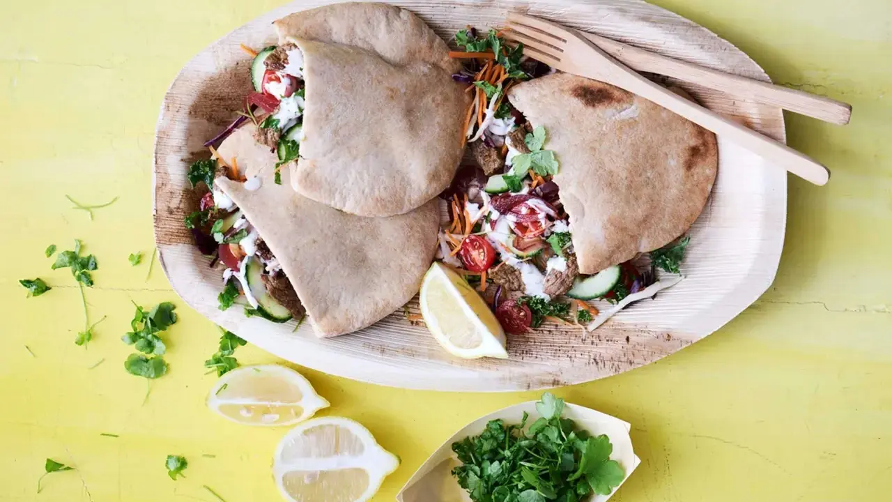 Läckra pitabröd fyllda med saftigt kött, grönsaker och en krämig sås. En härlig bit turkisk mat, serverad med citron och färska örter.