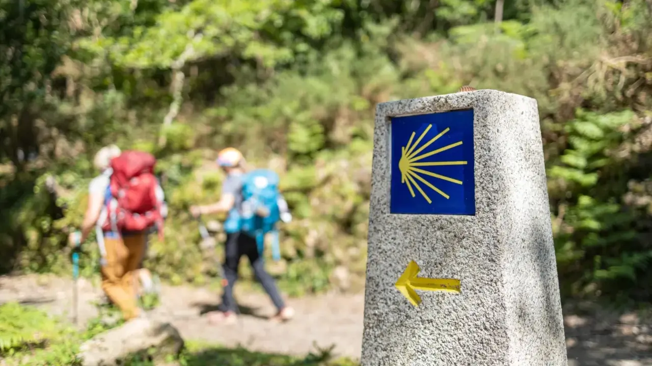 Pilgrimer på Santiago de Compostela vandring följer en sten med snäckskalssymbolen och en pil.