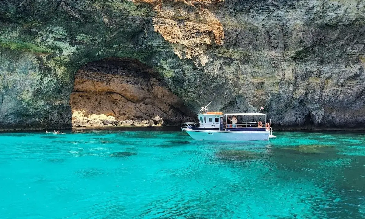 Båt vid en grotta med turkost vatten. En fantastisk vy av Maltas natur.