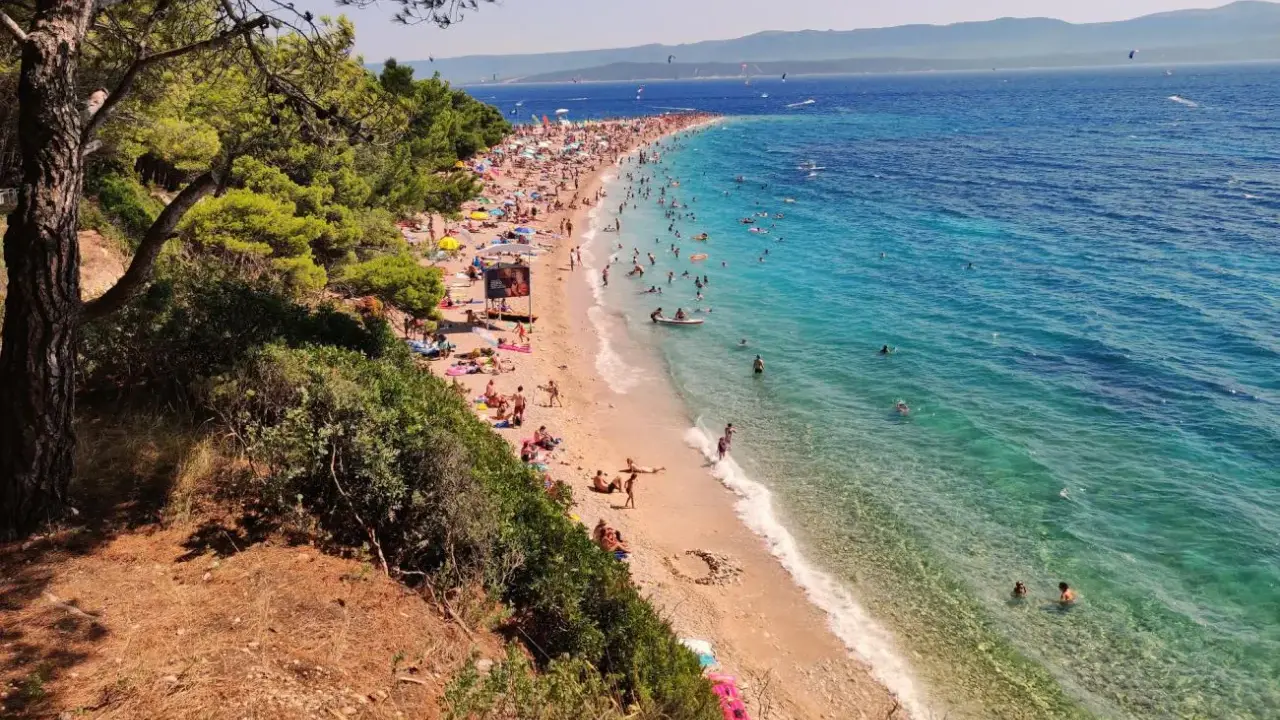 En solig dag på Zlatni Rat, en berömd strand med turkost vatten och många badande.