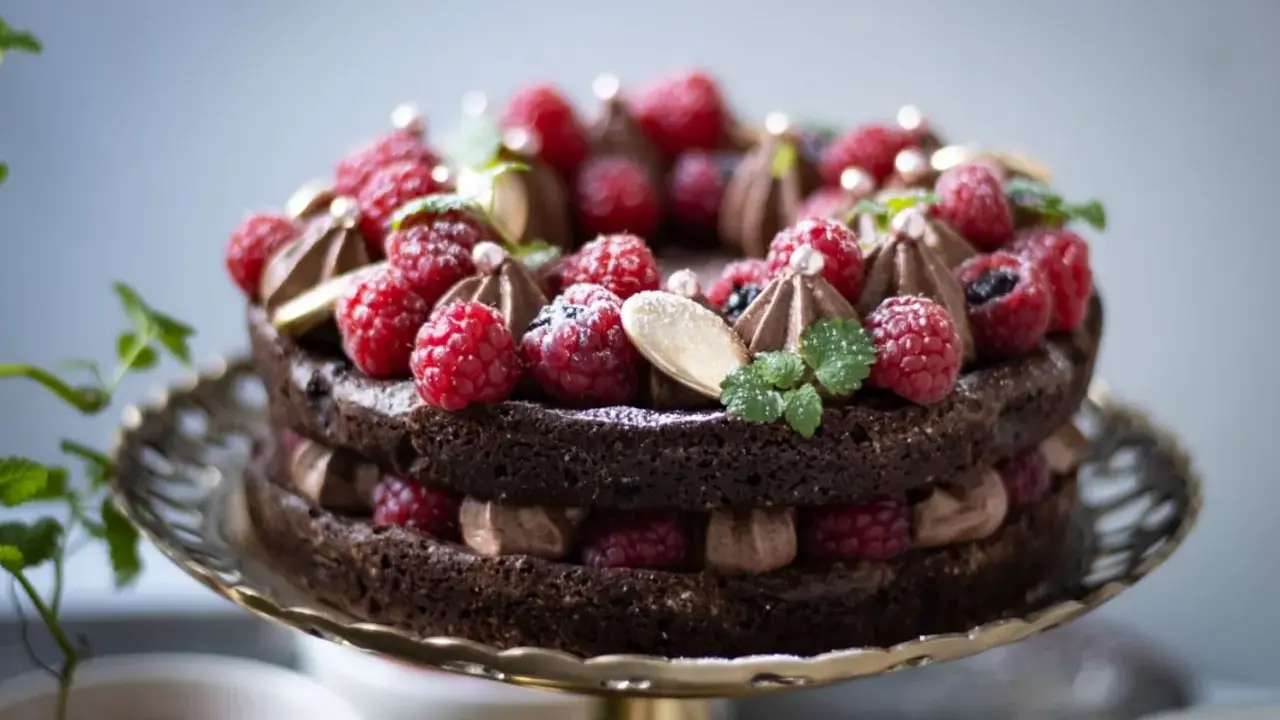 En lyxig kladdkaka med fluffig chokladmousse, toppad med färska hallon, mynta och guldkulor. Perfekt för en speciell fikastund.