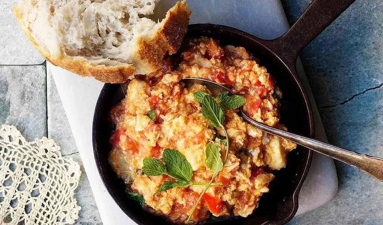 En smak av cypern mat: äggröra med tomat och örter i en gjutjärnspanna, serverad med ett gott bröd.