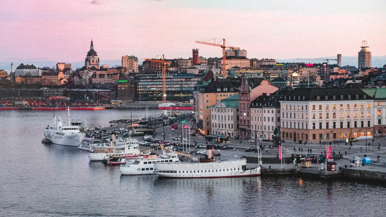 Stockholms silhuett med fartyg i hamnen vid solnedgången. En perfekt vy för att uppleva Stockholm.