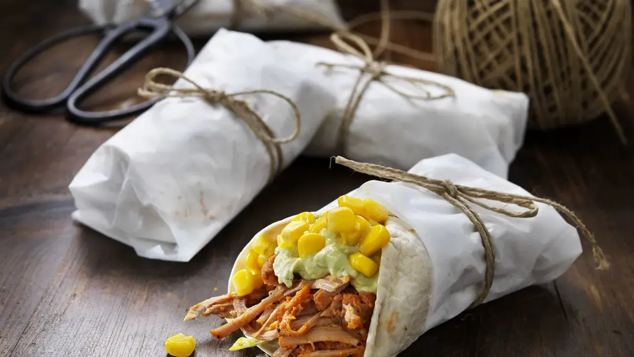 En läcker pulled pork wrap med majs och avokadokräm, inslagen i papper och bunden med snöre.