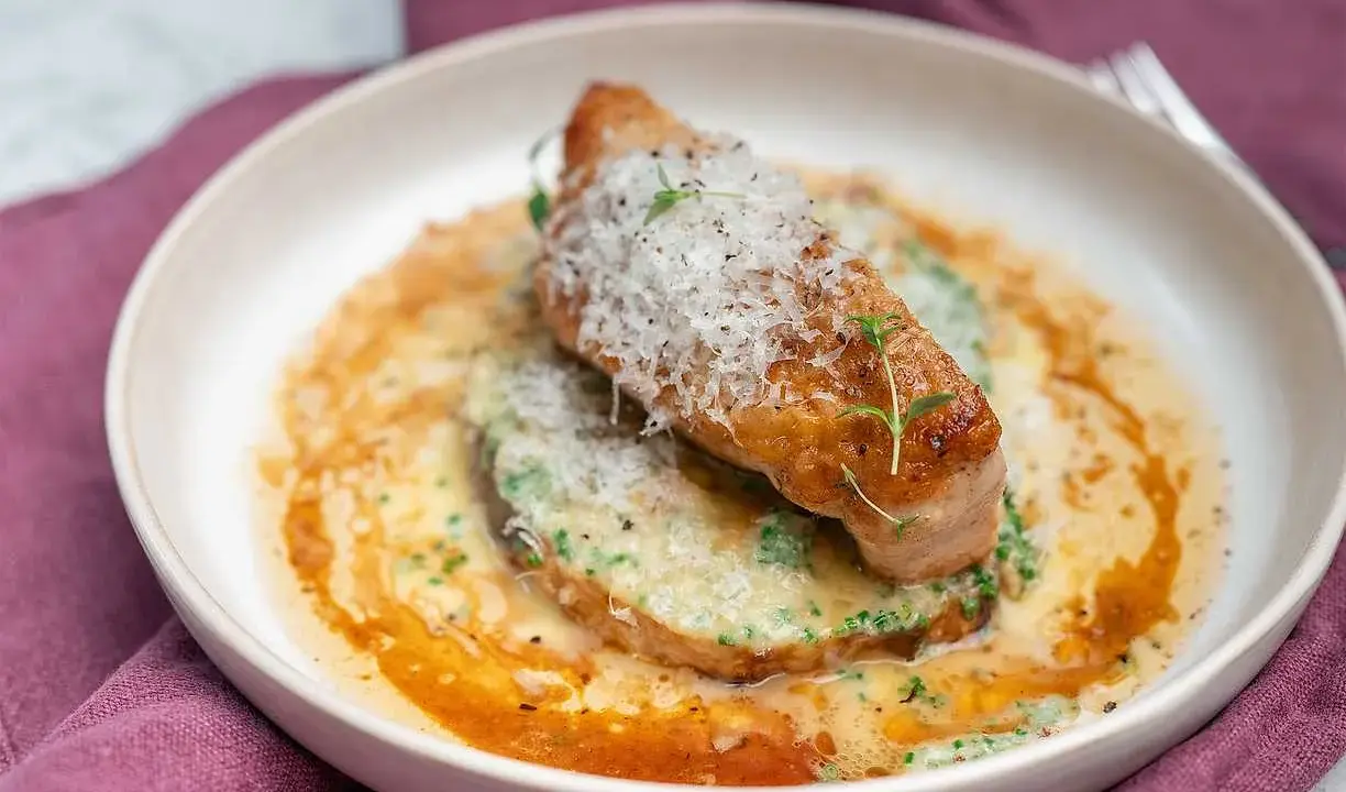 En elegant rätt med kött, grön puré och en krämig sås, toppad med riven ost och örter. Ett perfekt fine dining recept.