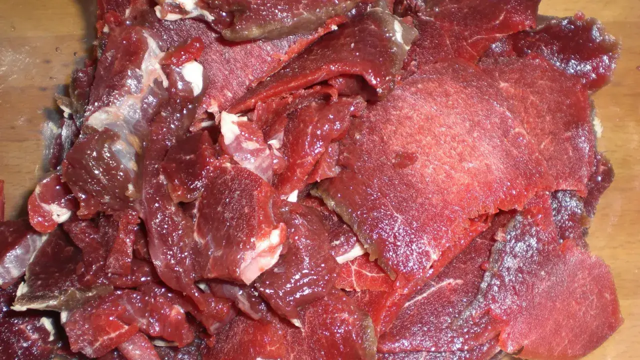 Råa, tunt skurna bitar av mörkrött kött, redo för ett läckert souvas recept.