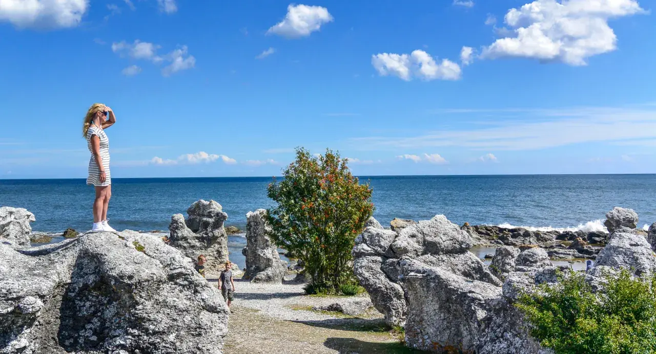 Flicka spanar ut över havet vid raukarna på Gotland. Bra tips för en solig dag!