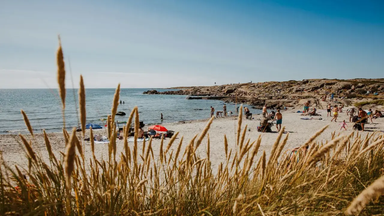 En solig stranddag i Halland med folk som badar och solar. Ett perfekt utflyktsmål för hela familjen.