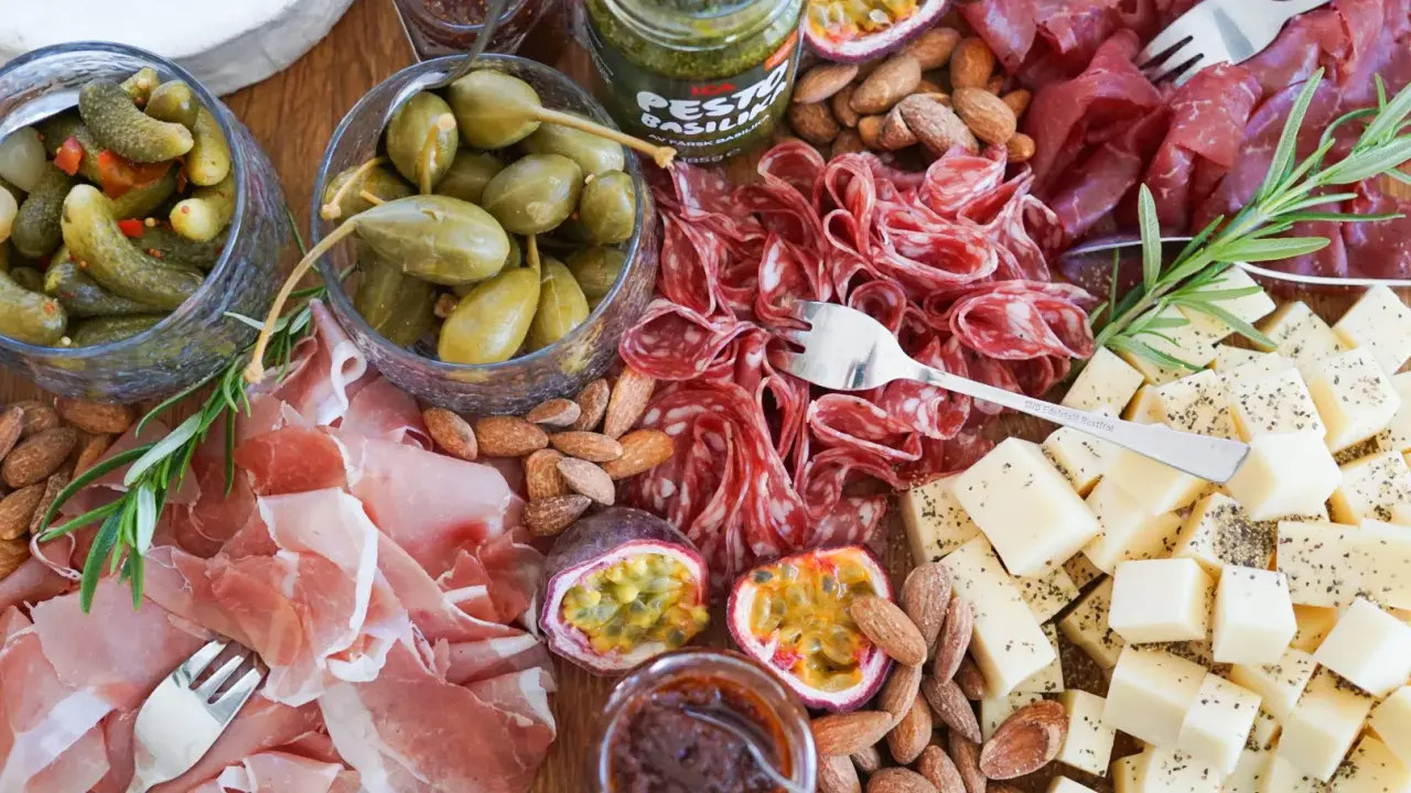 En härlig ost och charkbricka med salami, prosciutto, osttärningar, kapris, cornichoner, nötter och passionsfrukt.