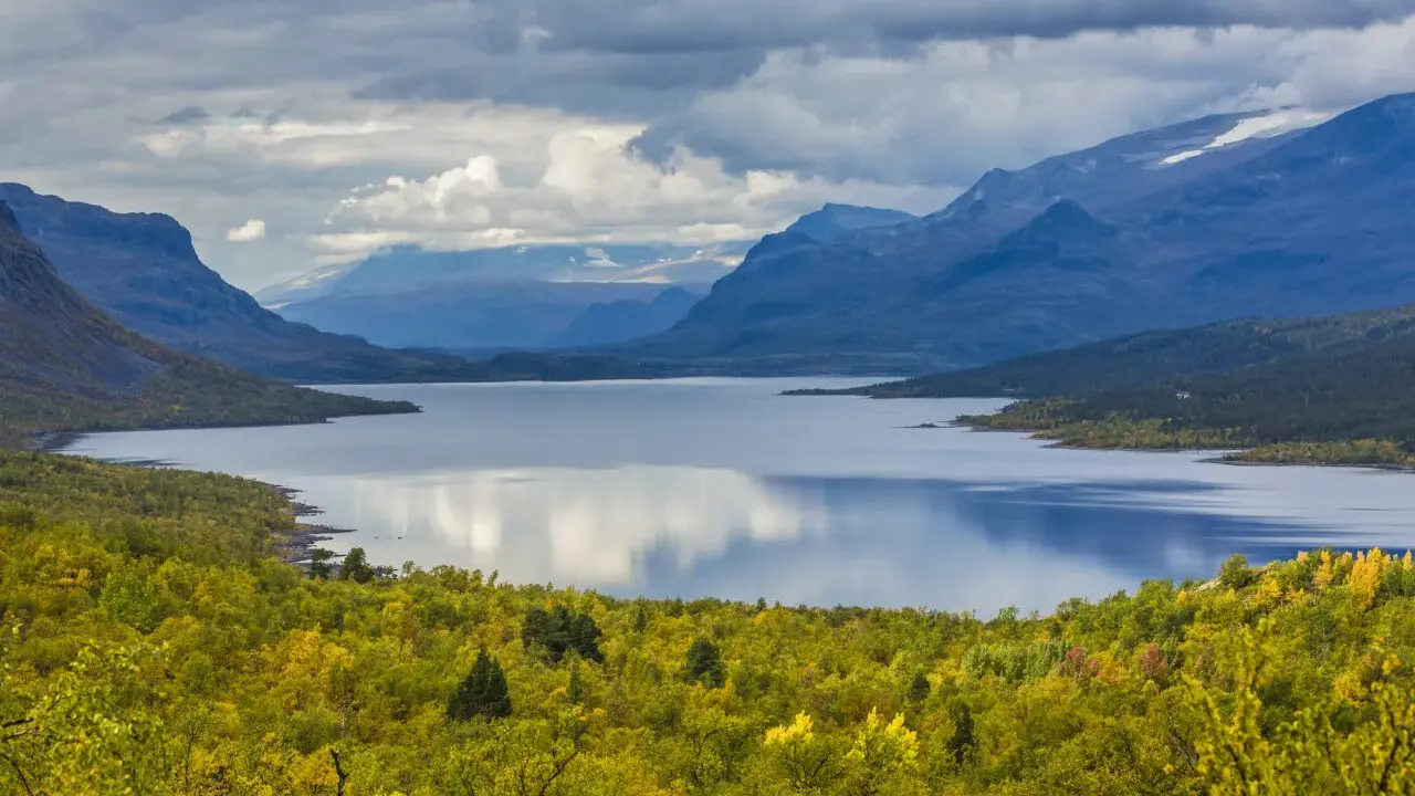 Vacker sjö omgiven av höstfärgad skog och berg. Perfekt för vandring dagsturer Sverige.