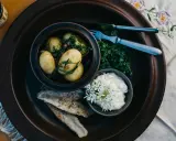 En rustik tallrik med nykokt färskpotatis, stekt fisk och en krämig sås. En härlig bit av finsk mat, redo att avnjutas.
