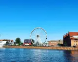 Stadsvy över Gdansk, Polen, med ett stort pariserhjul och byggnader längs floden.
