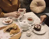 Två personer njuter av afternoon tea i Stockholm med smörgåsar och bakelser.