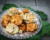 En silverbricka fylld med vackert formade vegetariska pizzabullar, dekorerade med små vita blommor och gröna blad.