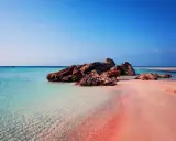 En rosa strand på Kreta med turkost vatten och klippor. En dröm för alla som älskar en kreta rosa strand.