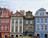 Färgglada husfasader i **Poznan, Polen**, med detaljerade ornament och tak. En byggkran syns i förgrunden.