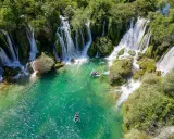 Vackra Kravice vattenfall med turkost vatten och båtar som glider fram. En idyllisk plats för avkoppling.