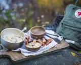 En härlig måltid med pasta och svamp, perfekt för att torka kyckling och njuta av naturen. En Fjällräven ryggsäck och vandringskängor syns i bakgrunden.