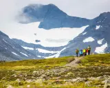 Vandringsgrupp på väg uppför en stenbelagd stig mot Sylarnas glaciärklädda toppar.
