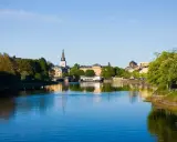Vacker vy över Klarälven med stadens silhuett, kyrktorn och grönska. En perfekt plats att se i Karlstad en solig dag.