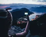 En person tar bild med mobiltelefonen av en stad vid havet i skymningen. En perfekt vy under en bilsemester Europa.