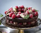 En lyxig kladdkaka med fluffig chokladmousse, toppad med färska hallon, mynta och guldkulor. Perfekt för en speciell fikastund.