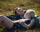 Ett par vilar i gräset efter en vandring i Vemdalen, skrattandes och njutandes av naturen.