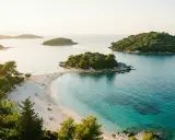 Vacker strand med turkost vatten och gröna öar. Perfekt för en resa till Albanien med tips om sol och bad.