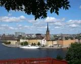 Vy över Riddarfjärden med en vit båt vid kajen, omgiven av Stockholms vackra byggnader. Perfekt för annorlunda utflykter i Stockholm.