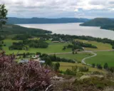 Vacker vy över en svensk sjö med grönskande landskap och en slingrande väg. En perfekt plats för upplevelser i Sverige.