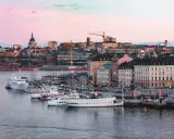 Stockholms silhuett med fartyg i hamnen vid solnedgången. En perfekt vy för att uppleva Stockholm.