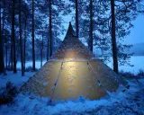 Varmt ljus lyser från ett snötäckt tält i Glaskogens naturreservat. En magisk vinterkväll.