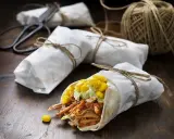 En läcker pulled pork wrap med majs och avokadokräm, inslagen i papper och bunden med snöre.