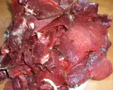 Råa, tunt skurna bitar av mörkrött kött, redo för ett läckert souvas recept.