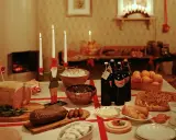 Julbord i Sverige med julmat som skinka, korv, risgrynsgröt och julmust. En tomte ljusstake lyser upp bordet.
