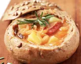 En mustig gryta med potatis och korv serveras i ett urgröpt bröd, en härlig tjeckisk matupplevelse.
