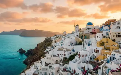 Vacker solnedgång över Oia, Santorini. Vita hus klättrar längs klippan ner mot det turkosblå havet. En dröm om en resa till Grekland.