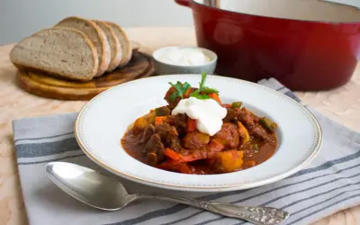 En portion mustig ungersk mat, en mustig gryta med kött och grönsaker, toppad med gräddfil och persilja. Serveras med gott bröd.