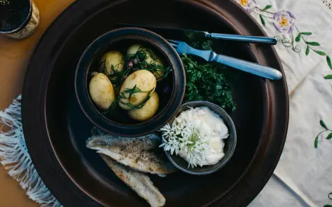 En rustik tallrik med nykokt färskpotatis, stekt fisk och en krämig sås. En härlig bit av finsk mat, redo att avnjutas.