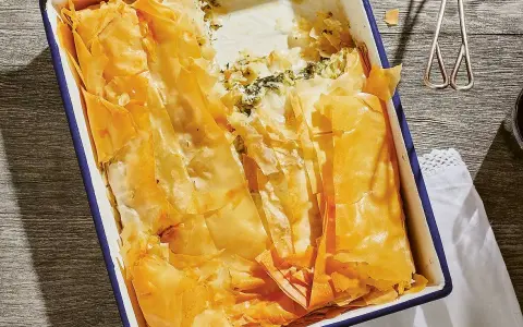 En gyllene, krispig spenatpaj i en blå kantad form. Perfekt för ett spanakopita recept.