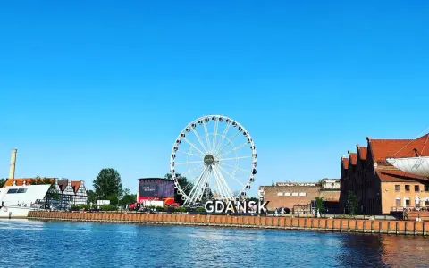 Stadsvy över Gdansk, Polen, med ett stort pariserhjul och byggnader längs floden.
