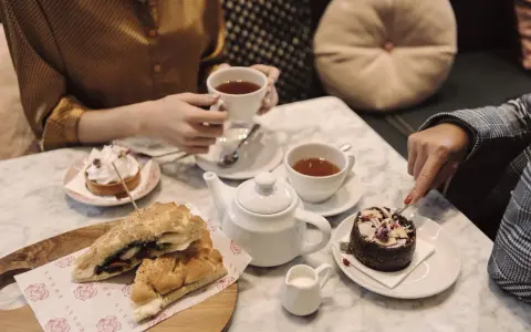 Två personer njuter av afternoon tea i Stockholm med smörgåsar och bakelser.