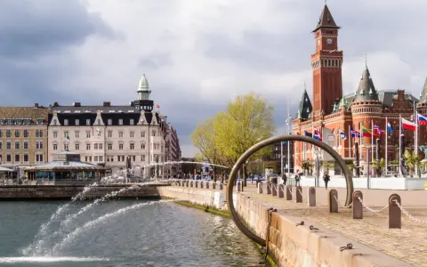 Vattenfontäner vid hamnen i Helsingborg, med Rådhuset i bakgrunden. Perfekt för en promenad bland sevärdheter.