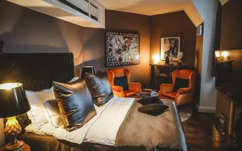 Ett lyxigt rum på Lydmar hotell med en stor säng, två orangea fåtöljer och konst på väggarna.