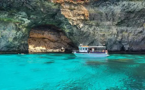 Båt vid en grotta med turkost vatten. En fantastisk vy av Maltas natur.