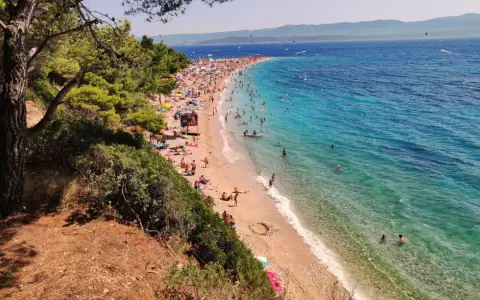 En solig dag på Zlatni Rat, en berömd strand med turkost vatten och många badande.